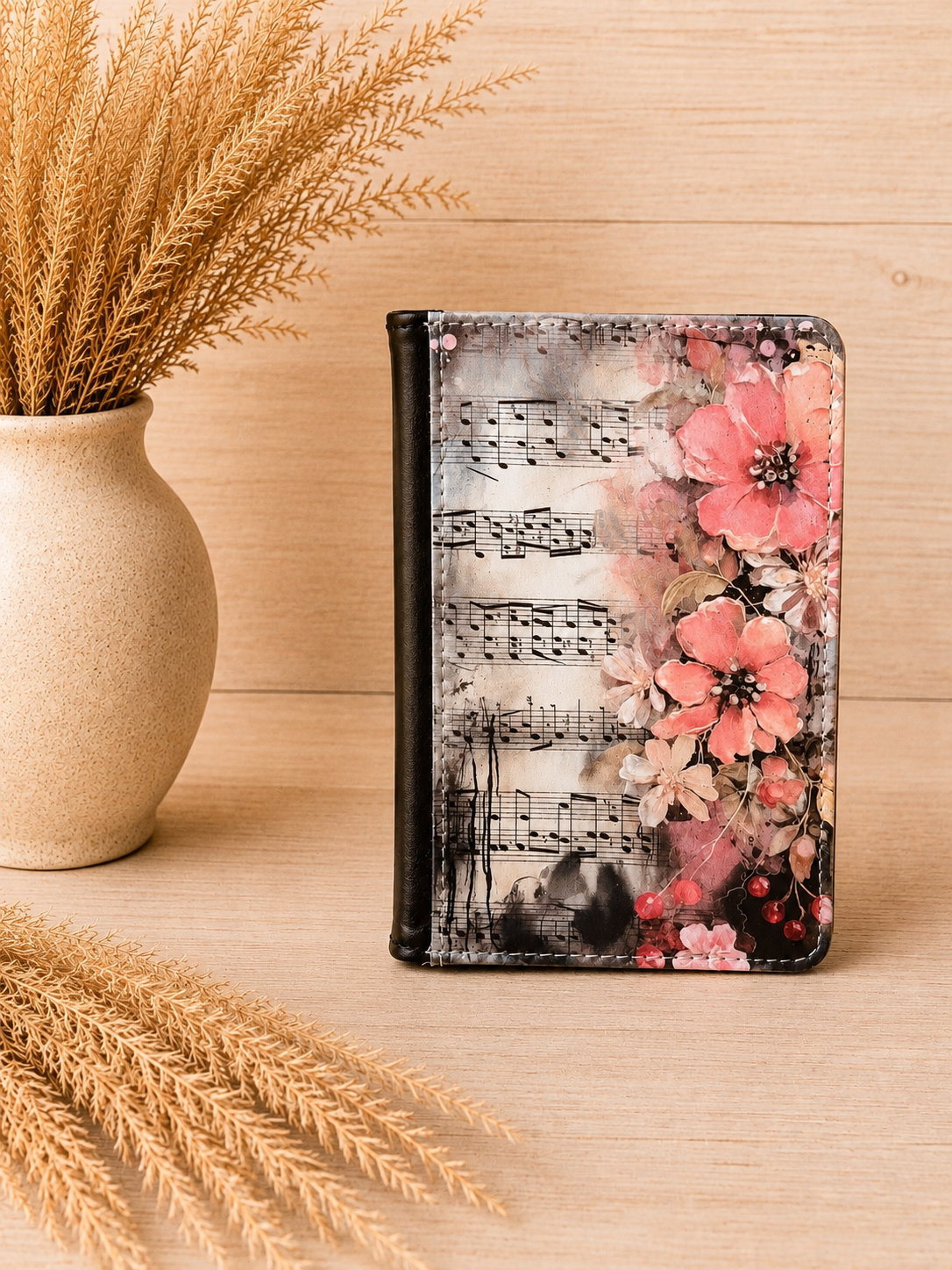 Pink floral music passport holder with sheet music design displayed on a neutral boho wood background with pampas grass